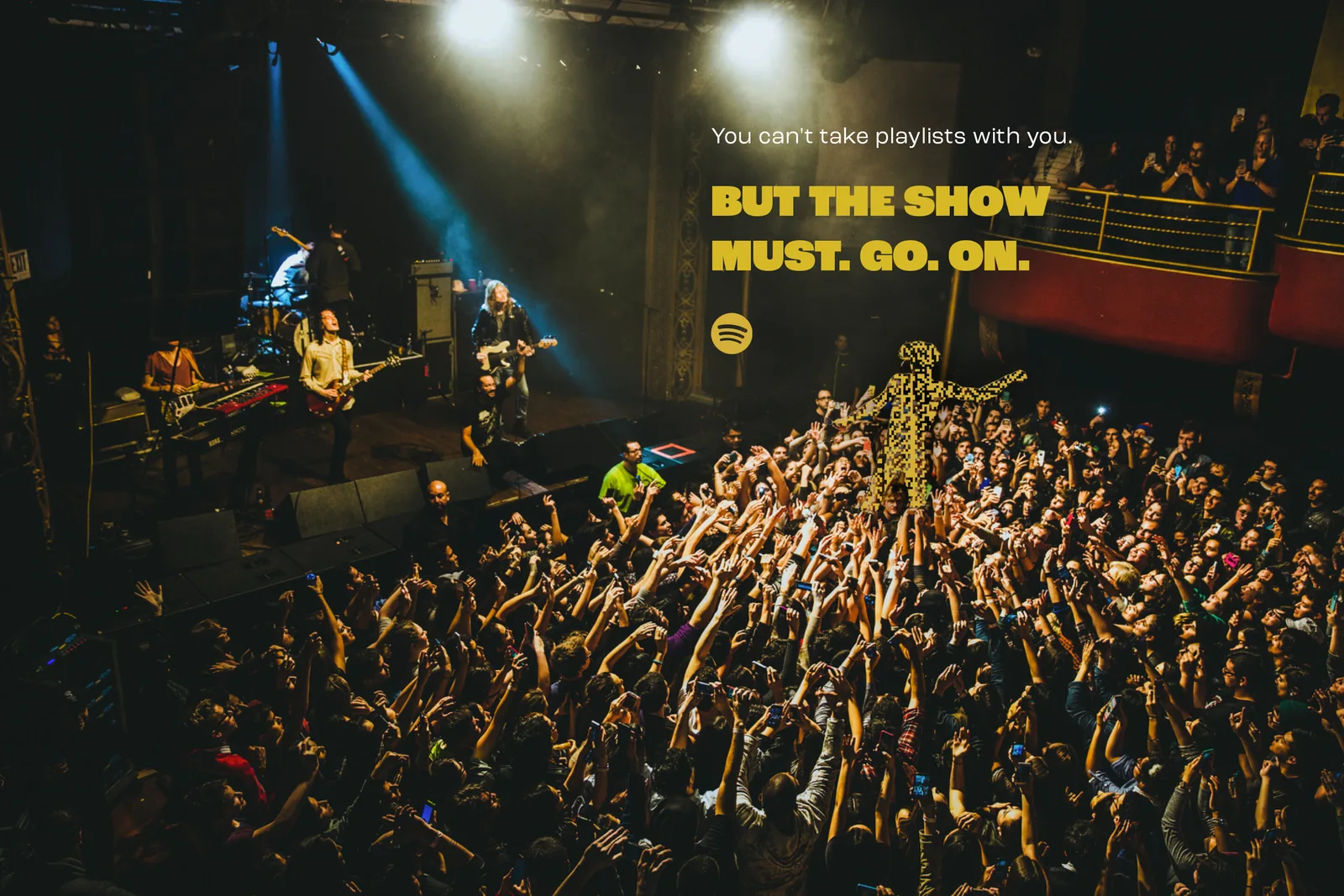 Overhead club shot, band onstage, a gold code crowdsurfer. Headline, You can't take playlists with you. But the show must. Go. On.